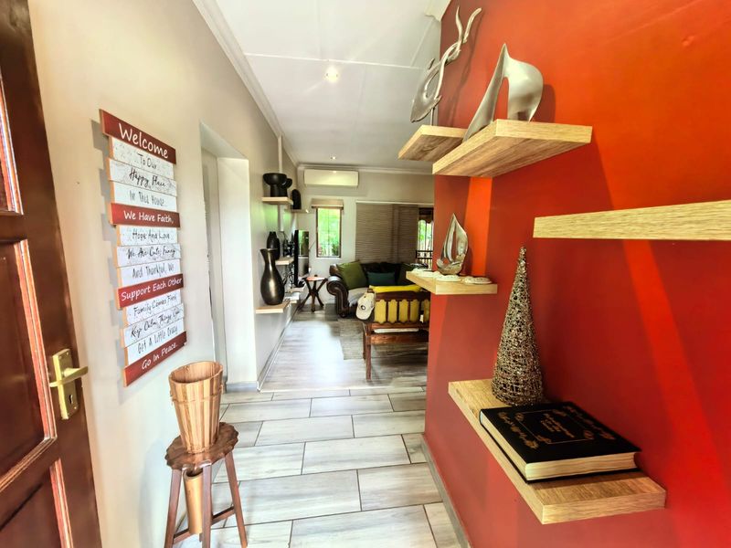 Entrance hallway featuring tiled flooring, recessed lighting, and a bold accent wall with built-in shelving, leading into the main living area.