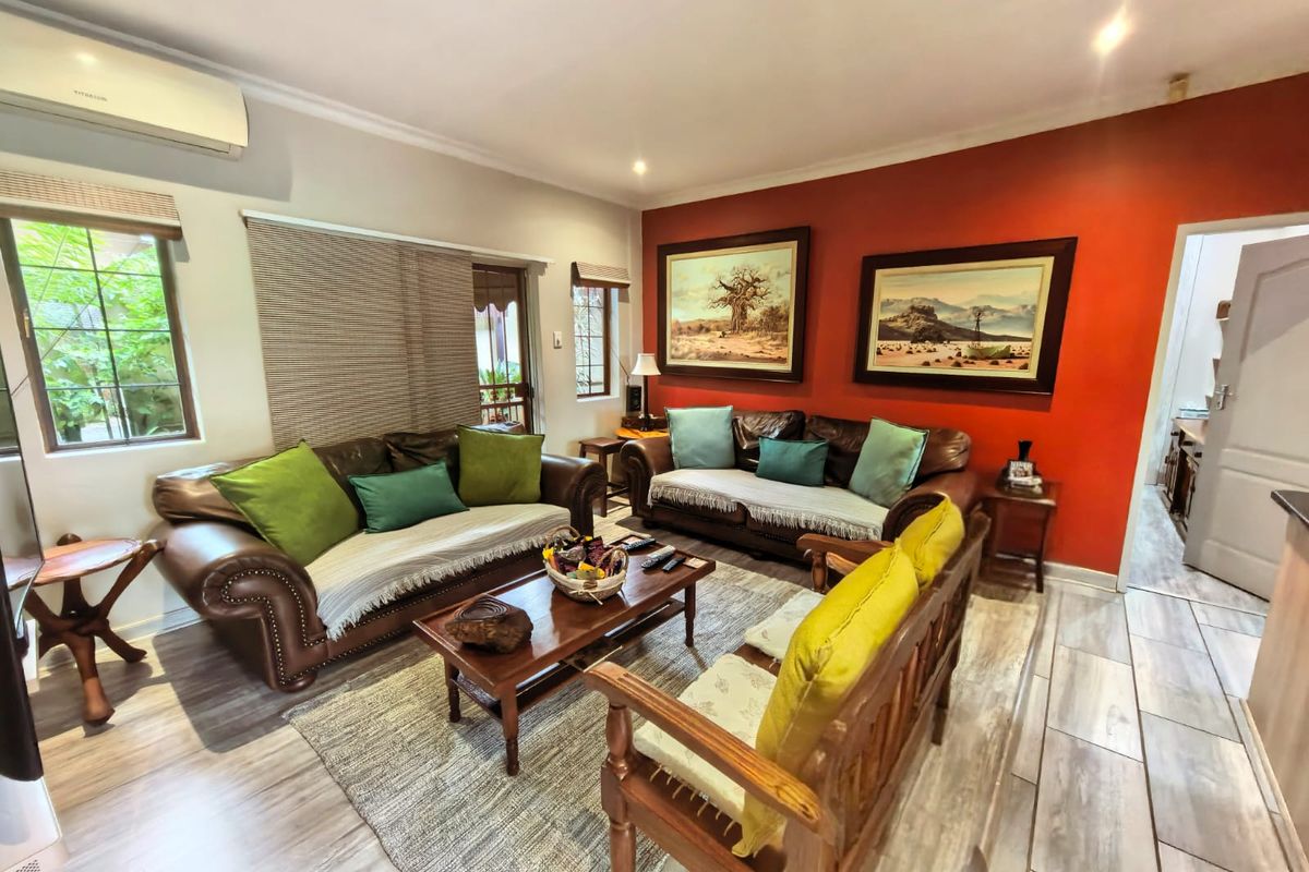 A comfortable living room featuring wood-look tile flooring, an accent wall, and a wall-mounted air conditioning unit.