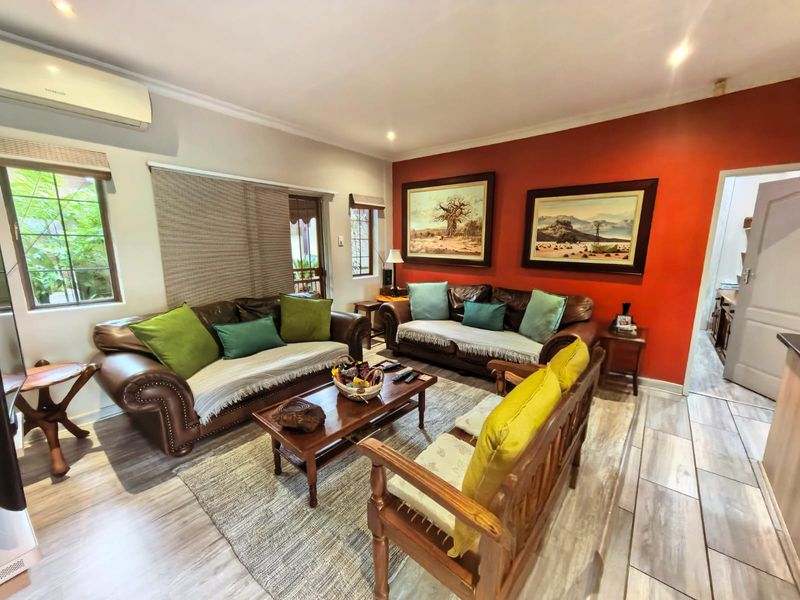 A comfortable living room featuring wood-look tile flooring, an accent wall, and a wall-mounted air conditioning unit.