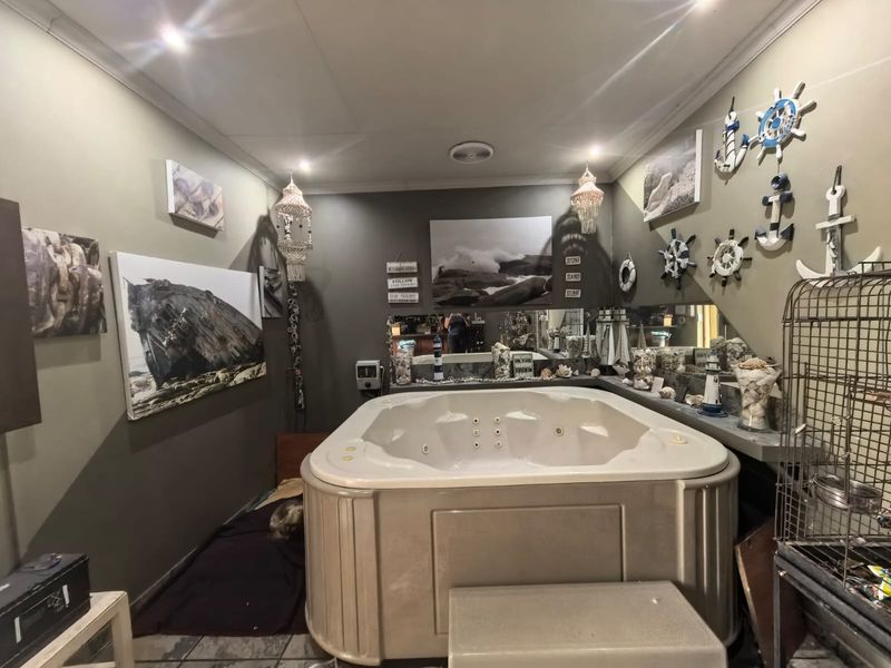 A bathroom featuring a large built-in spa bath, mirrored wall, and recessed lighting, offering a dedicated space for relaxation.