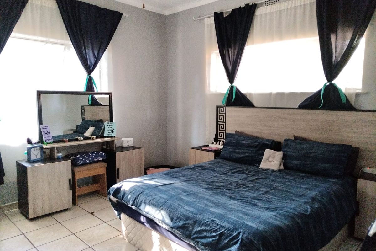 A bedroom featuring tiled flooring, a built-in headboard, and a built-in vanity unit with a mirror.