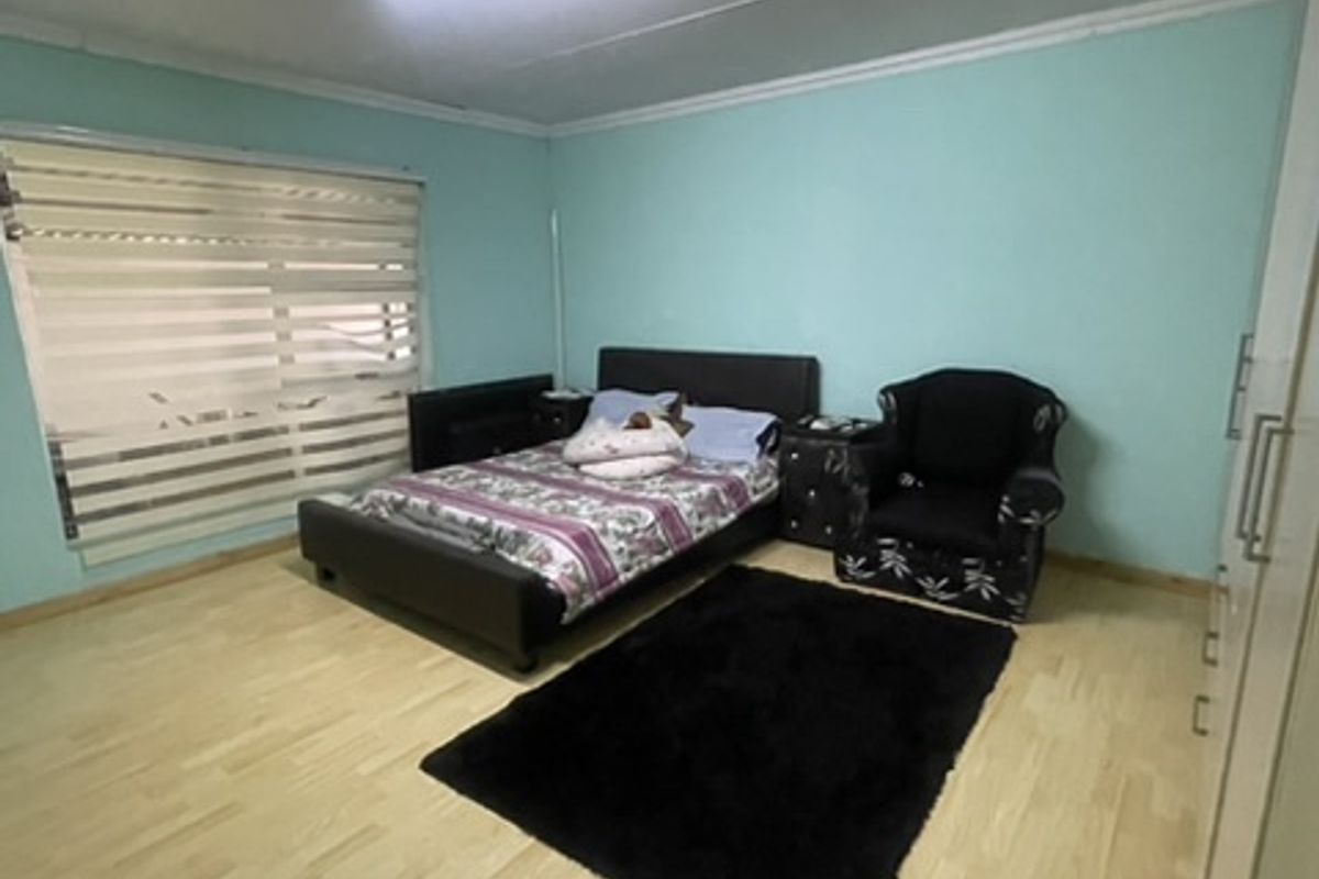 A bedroom featuring light-toned laminate flooring, built-in wardrobe storage, and modern zebra blinds, providing a functional and neutral living space.