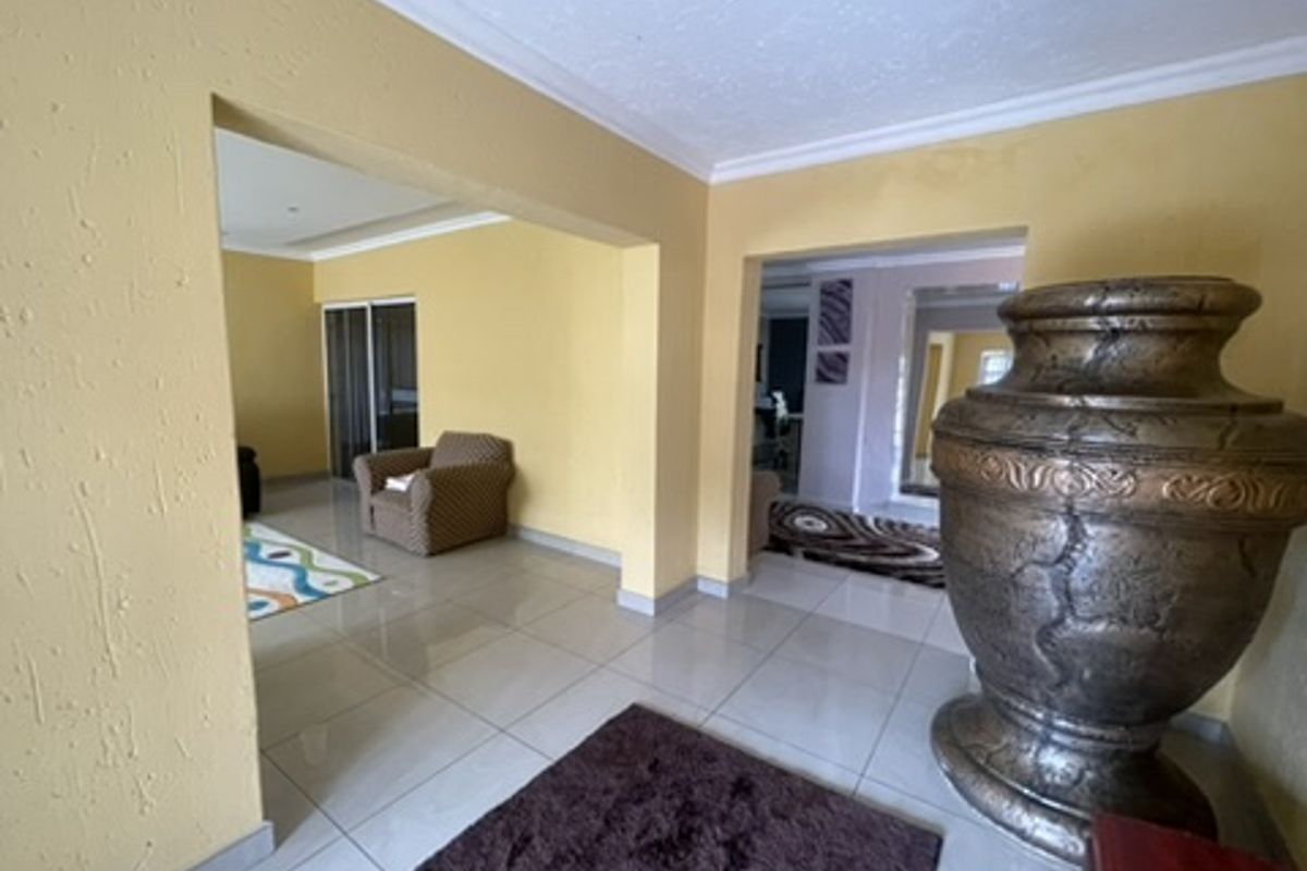 An open-plan living area featuring tiled flooring, coved ceilings, and distinct archways connecting to adjacent rooms.