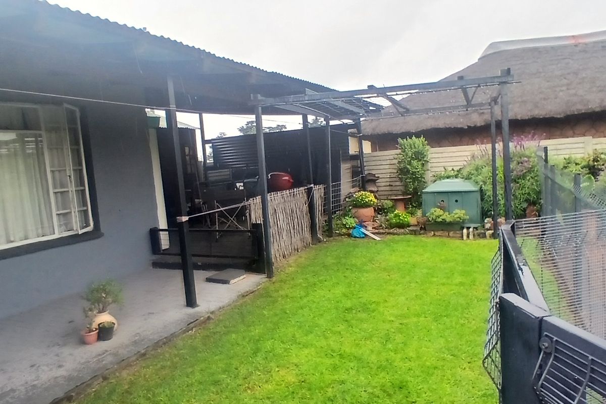 Rear garden area featuring a covered patio, lawn, and adjacent swimming pool with perimeter fencing.