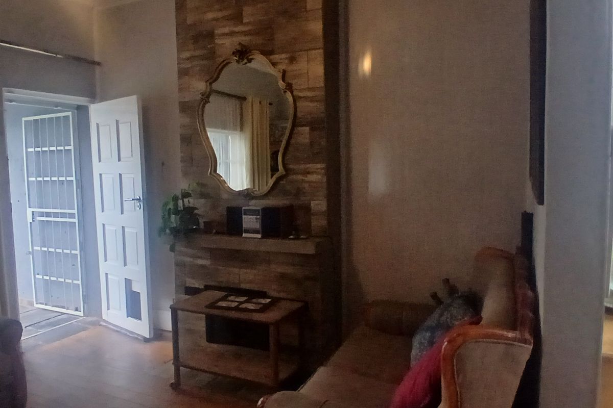 A living room featuring a prominent wood-look tiled fireplace surround and timber flooring, with direct access to an exterior doorway.