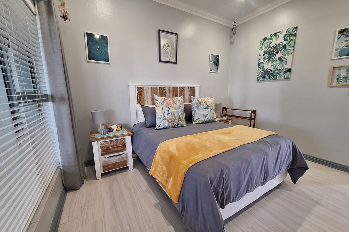 A well-maintained bedroom featuring neutral wall tones, crown molding, and light-colored wood-look flooring.