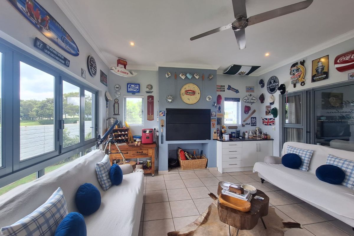 A spacious living room featuring tiled flooring, recessed lighting, a ceiling fan, and built-in cabinetry, with large windows providing natural light.