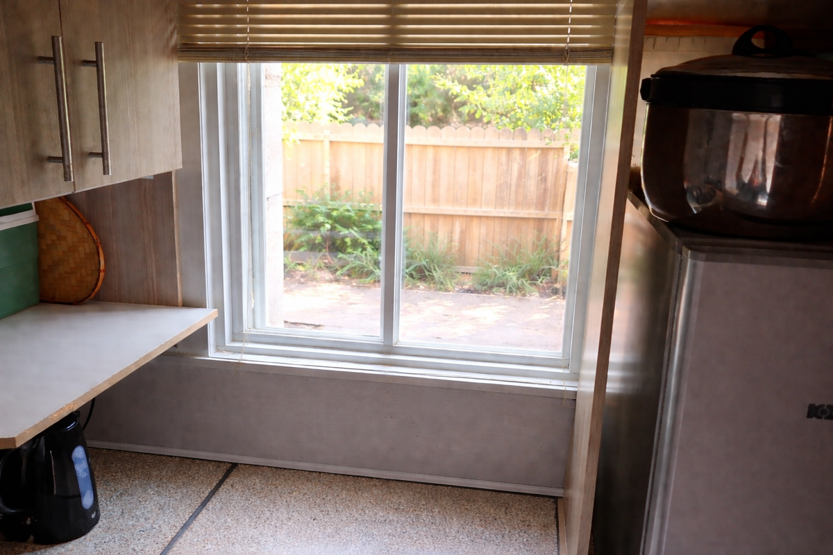 A functional kitchen area featuring laminate countertops, built-in cabinetry, and a window overlooking the rear garden area.