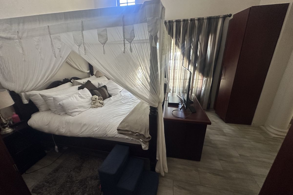 A spacious bedroom featuring tiled flooring and a built-in cupboard, offering a comfortable layout with natural light.