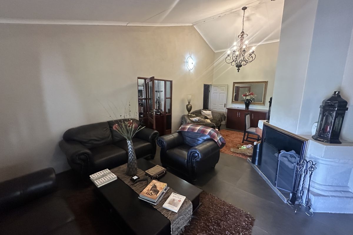 Spacious living room featuring a vaulted ceiling, a built-in fireplace, and tiled flooring, offering a comfortable and traditional living space.