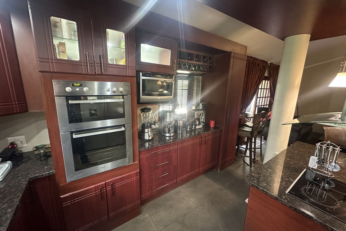 A well-appointed kitchen featuring dark wood cabinetry, granite countertops, a built-in double oven, and a built-in microwave, with an open-plan layout.
