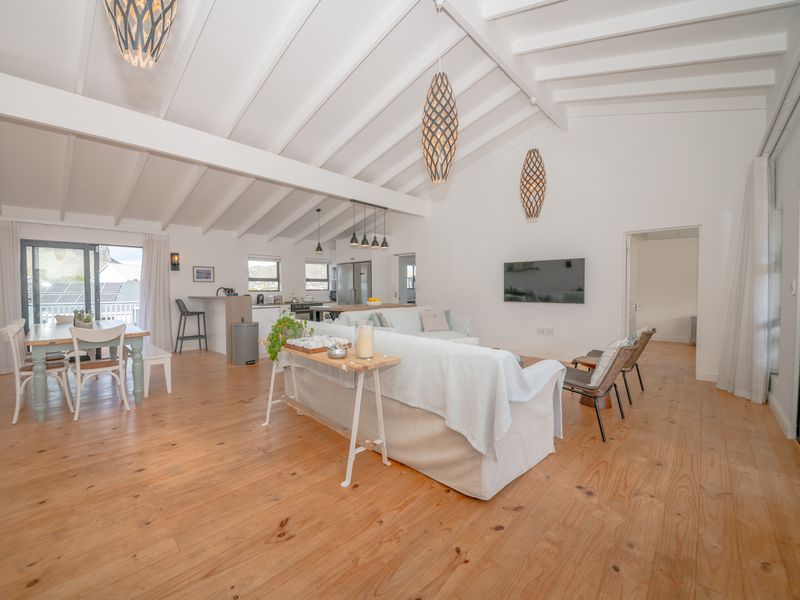 Spacious open-plan living and dining area featuring high exposed beam ceilings, natural timber flooring, and a modern kitchen with a central island.