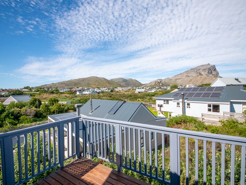 An elevated timber balcony offering expansive views of the surrounding neighborhood, mountains, and neighboring properties with solar installations.