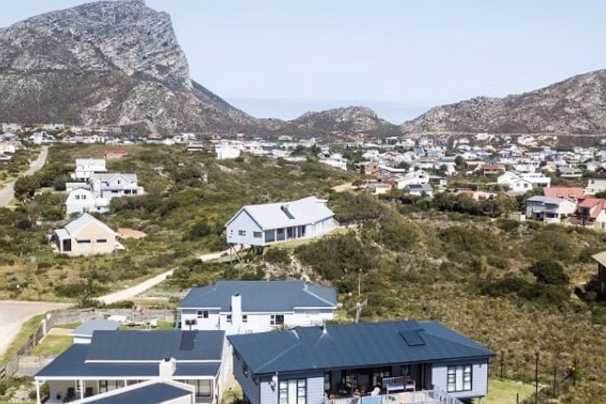 Aerial view of a residential property featuring a metal roof, elevated deck, and surrounding landscape in a coastal or mountainous setting.