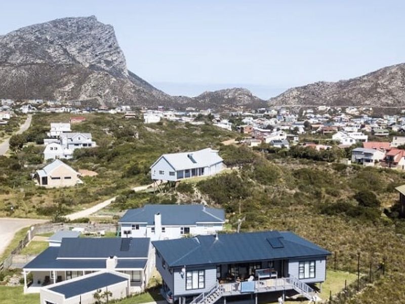 Aerial view of a residential property featuring a metal roof, elevated deck, and surrounding landscape in a coastal or mountainous setting.