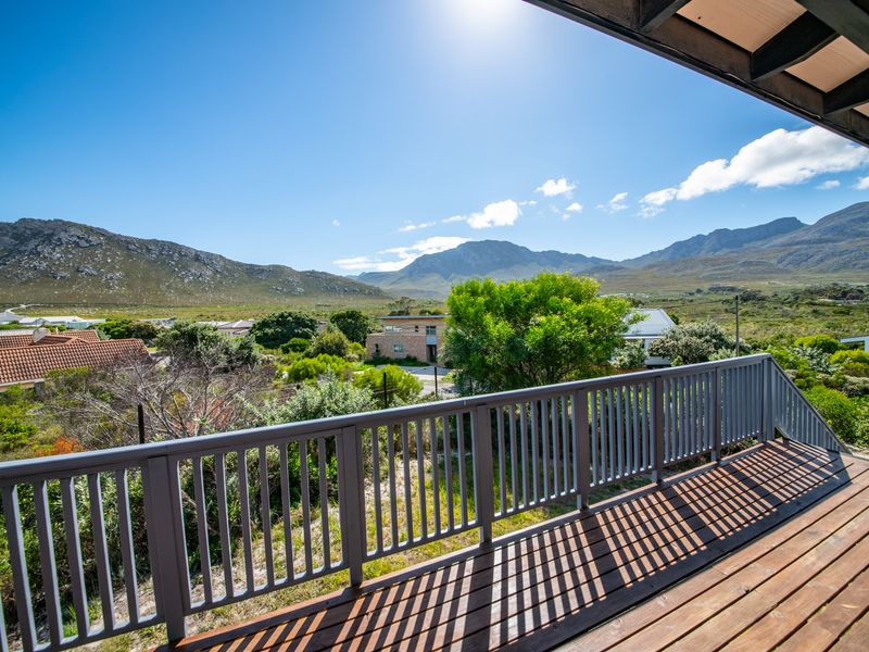 An elevated timber balcony featuring a secure railing, offering expansive views of the surrounding landscape and mountain range.