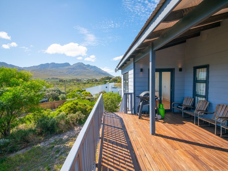 A spacious elevated timber deck patio featuring a metal balustrade and corrugated roof, offering scenic mountain and landscape views.