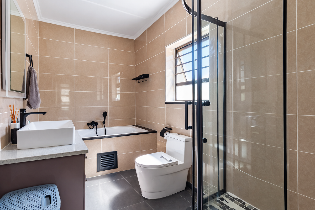 Modern bathroom featuring a built-in vanity with countertop basin, a separate bathtub, and a glass-enclosed shower with neutral wall tiling.