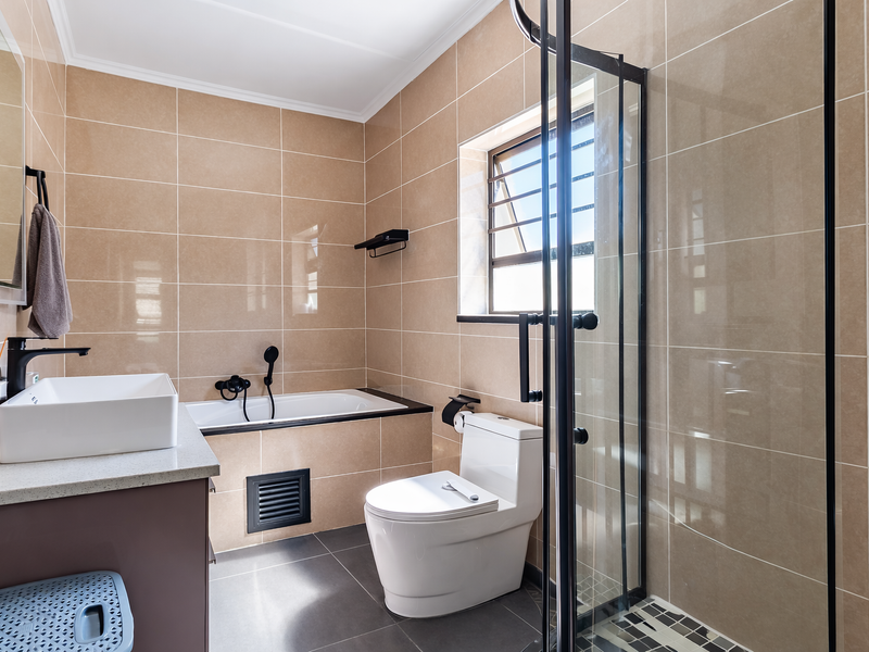 Modern bathroom featuring a built-in vanity with countertop basin, a separate bathtub, and a glass-enclosed shower with neutral wall tiling.