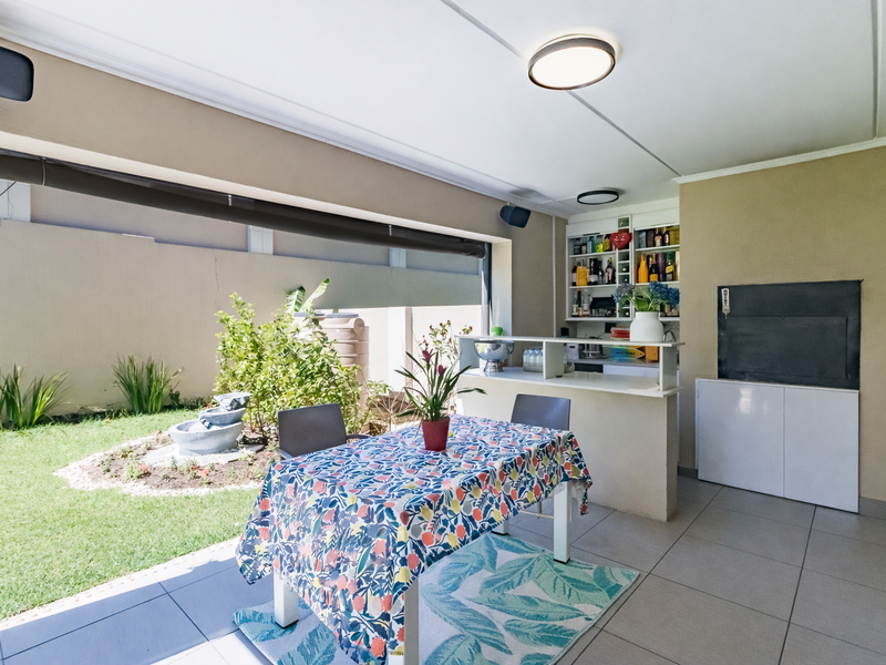 Covered patio area featuring a built-in bar counter, integrated shelving, and direct access to a private garden space.