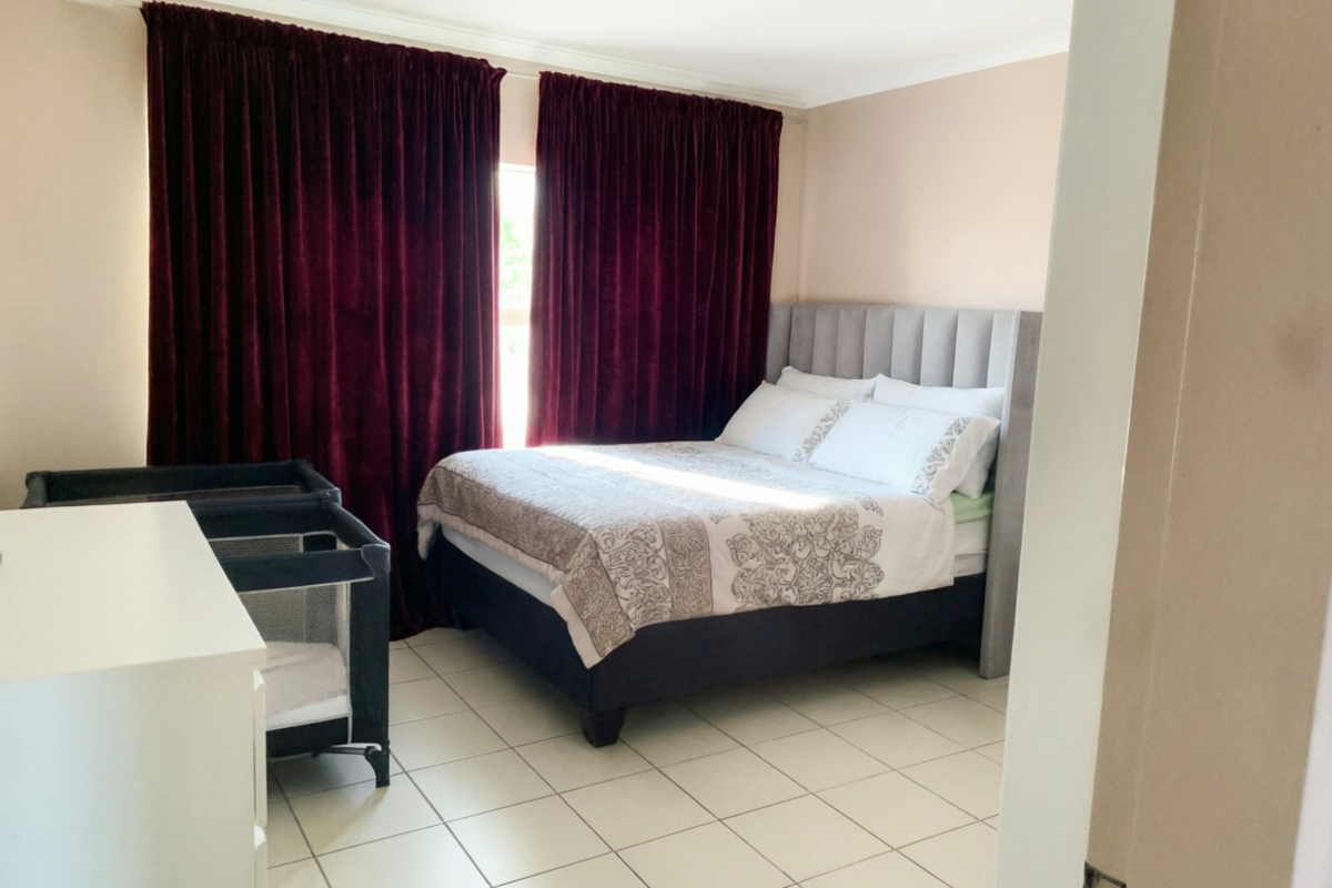 A bedroom featuring tiled flooring and coved ceiling details, currently furnished with a bed and a portable crib.