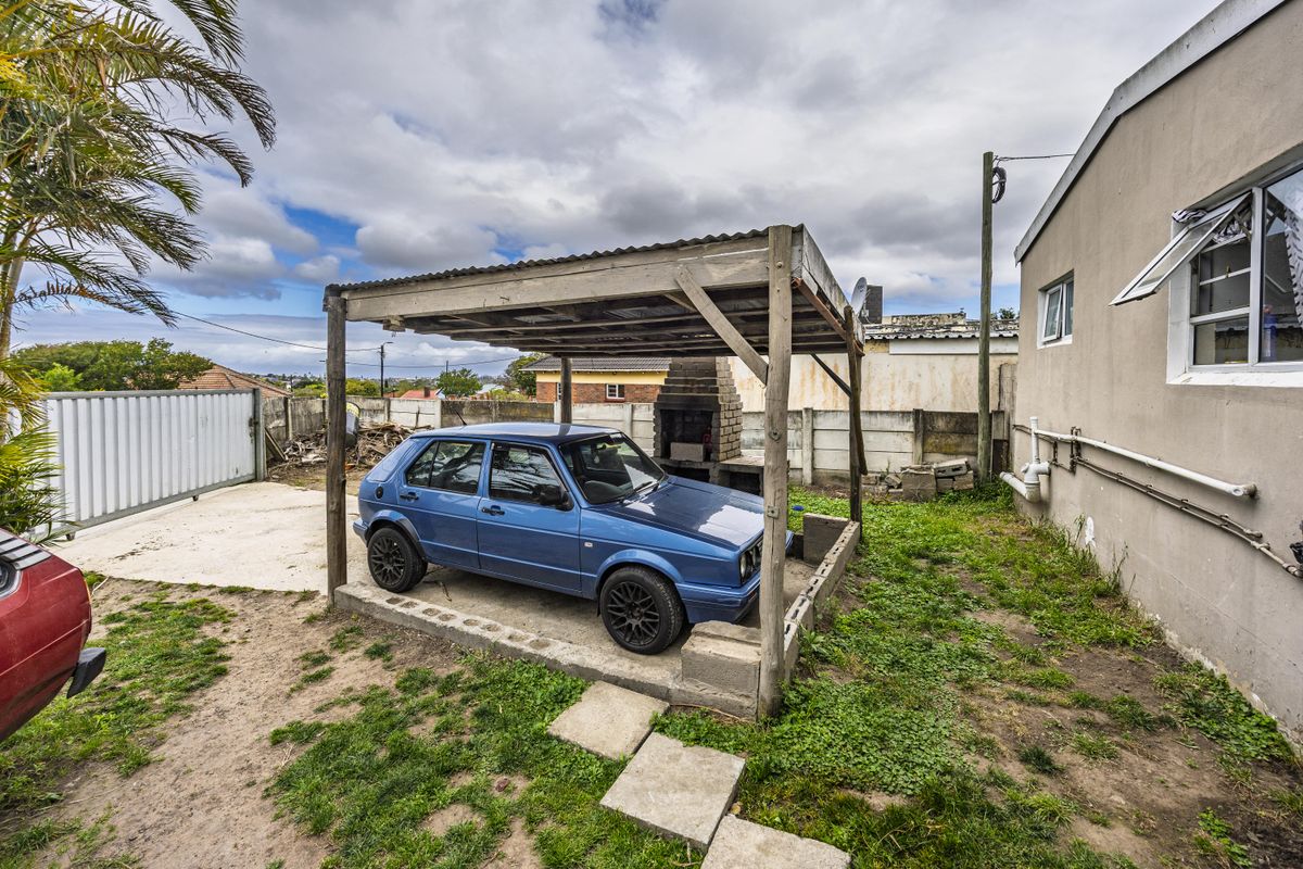 Rear yard area featuring a timber carport structure, a built-in brick braai, and perimeter boundary walling.