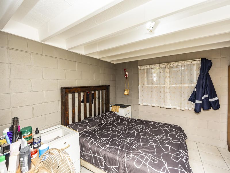 A bedroom featuring exposed beam ceilings, cinder block walls, and tiled flooring, offering a functional space with potential for cosmetic updates.