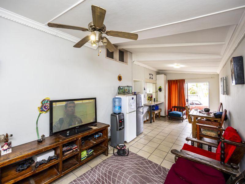 Open-plan living area featuring tiled flooring, a ceiling fan, and direct access to the exterior through a sliding glass door.