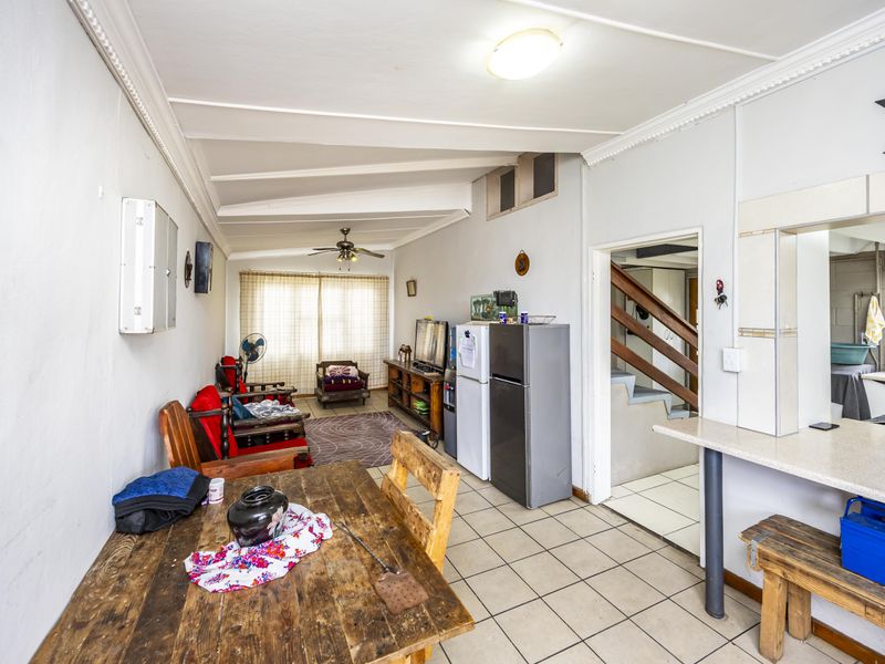 Open plan living and dining area featuring tiled flooring, a breakfast bar, and direct access to a staircase.