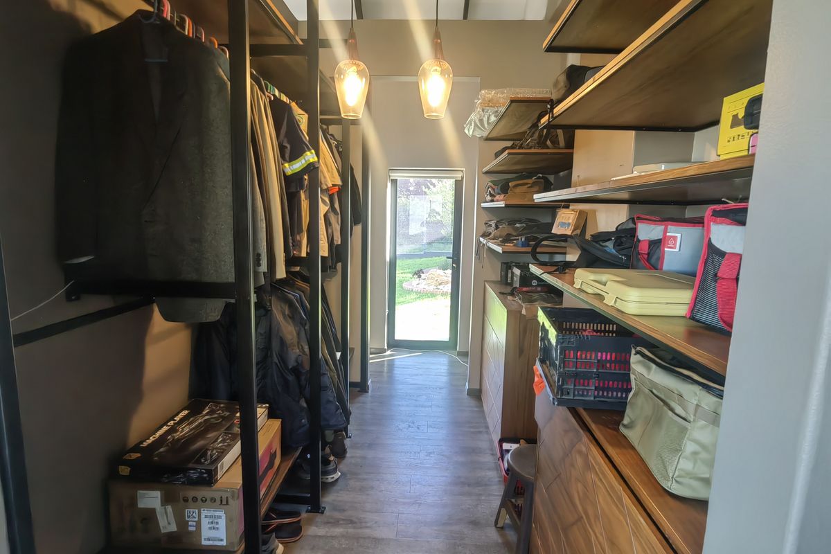 A walk-in closet or dressing area featuring custom industrial-style metal and wood shelving, pendant lighting, and direct access to the exterior.