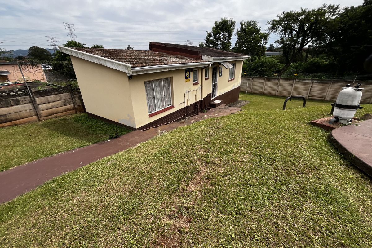 Rear view of the property showing the exterior facade, garden area, and pool pump infrastructure.
