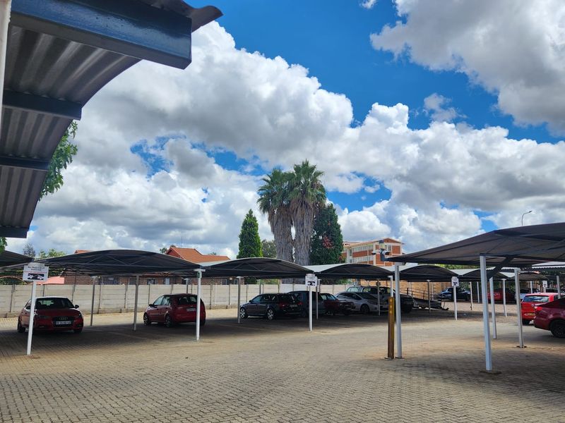 An open-air parking area featuring covered carports and paved ground surfaces within a secure complex.