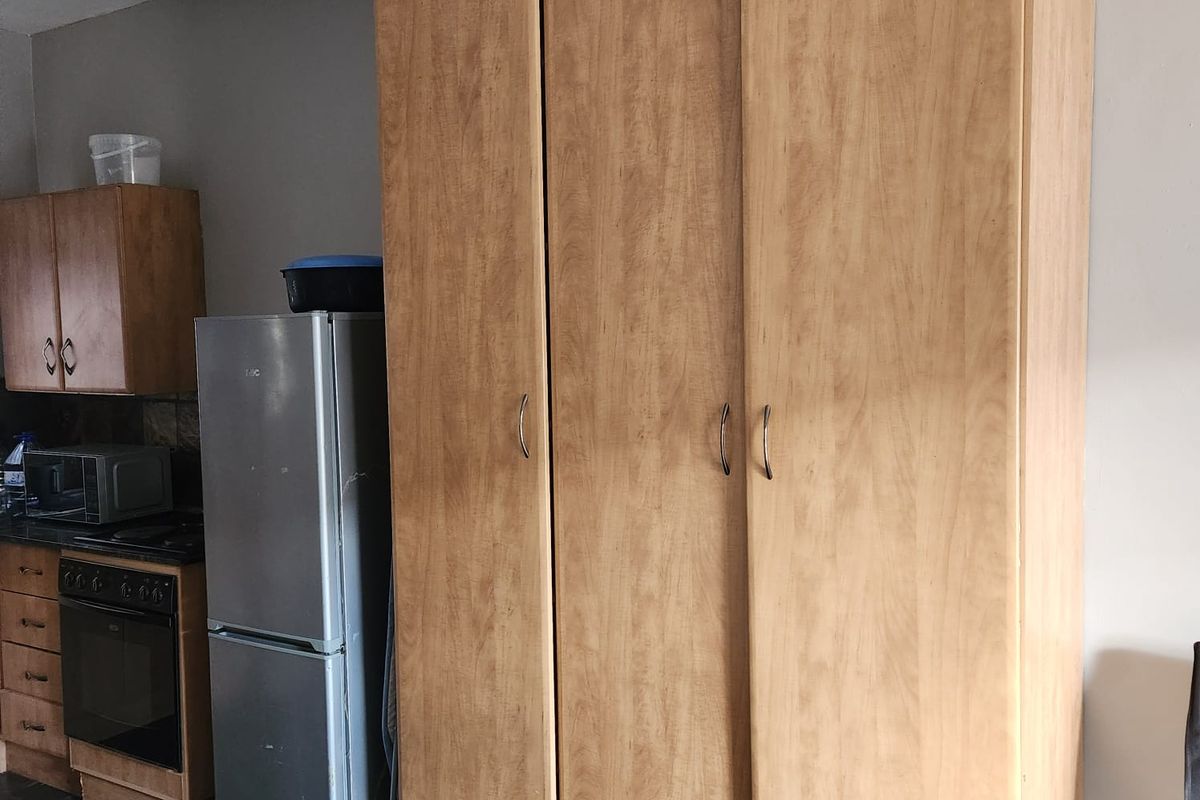 A kitchen area featuring built-in cabinetry, an integrated oven and hob, and a large built-in wardrobe providing additional storage space.