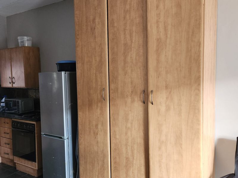 A kitchen area featuring built-in cabinetry, an integrated oven and hob, and a large built-in wardrobe providing additional storage space.