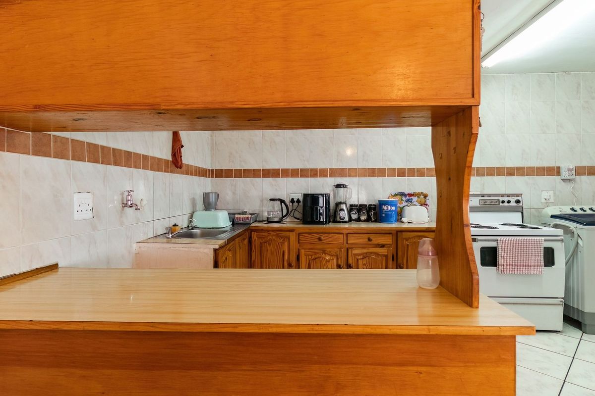 A functional kitchen featuring wooden cabinetry, tiled splashbacks, and a breakfast bar counter, providing a practical layout for daily meal preparation.