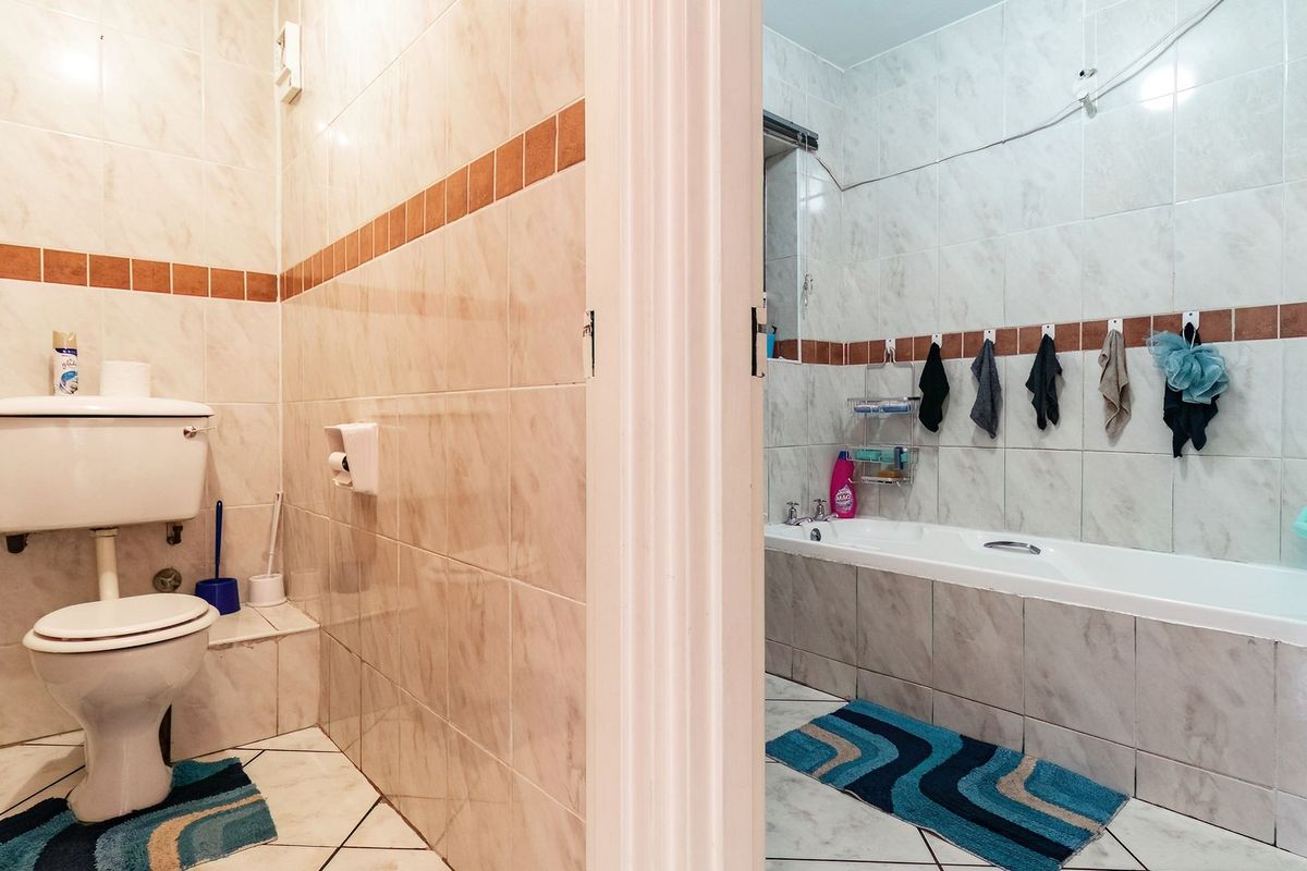 A functional bathroom featuring a separate toilet area and a bathtub with tiled walls and flooring.
