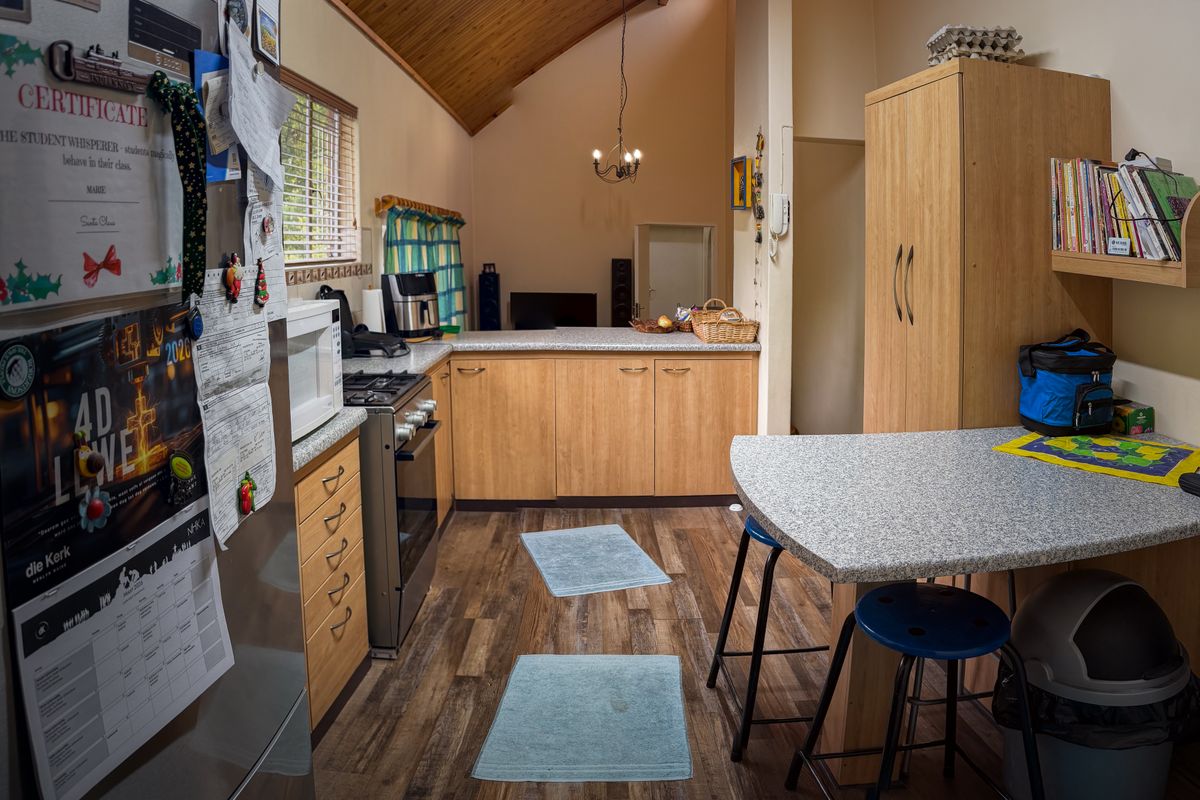 A functional kitchen featuring laminate cabinetry, gas stove, and a vaulted timber ceiling, with an integrated breakfast nook and ample storage space.