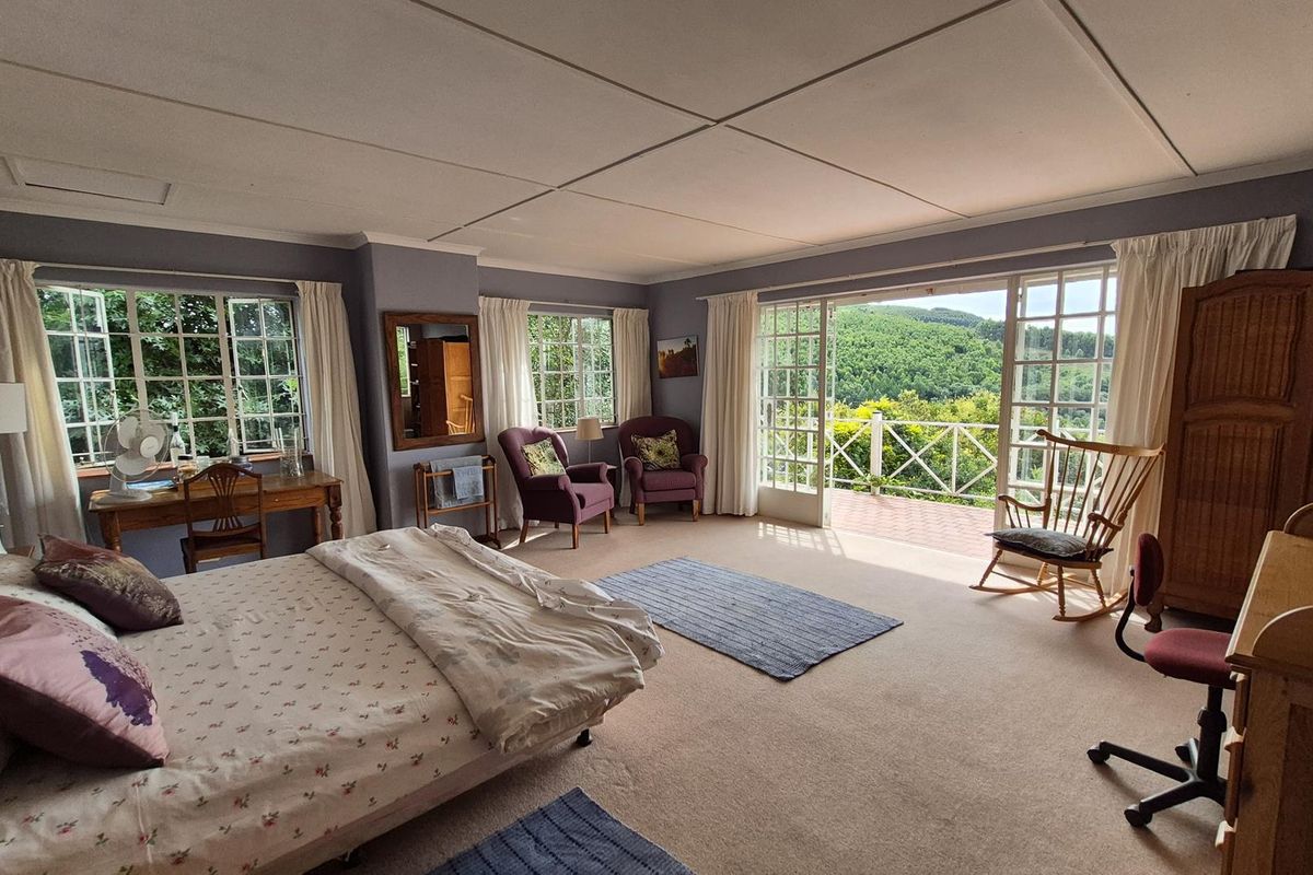 Spacious bedroom featuring large windows, carpeted flooring, and direct access to a private balcony with scenic landscape views.