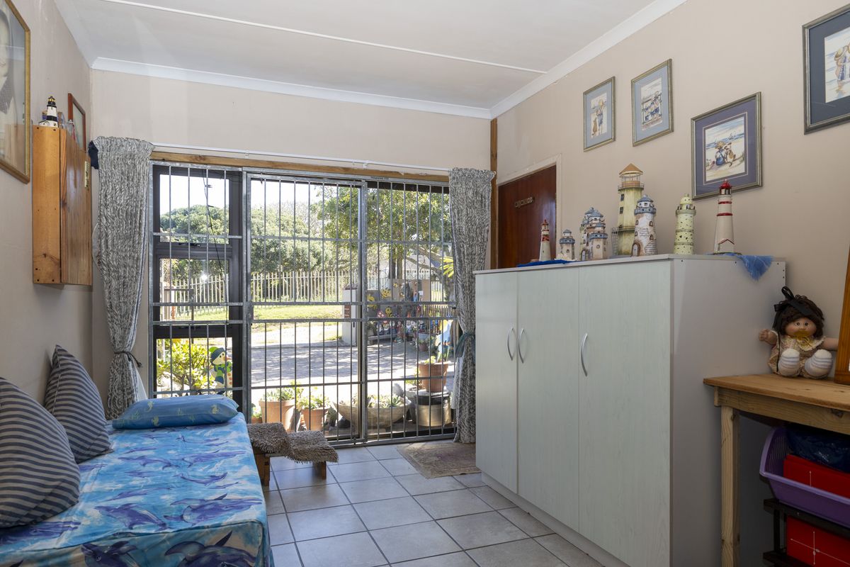 A bedroom featuring tiled flooring, a built-in cupboard, and a sliding glass door with a security gate providing access to the exterior.