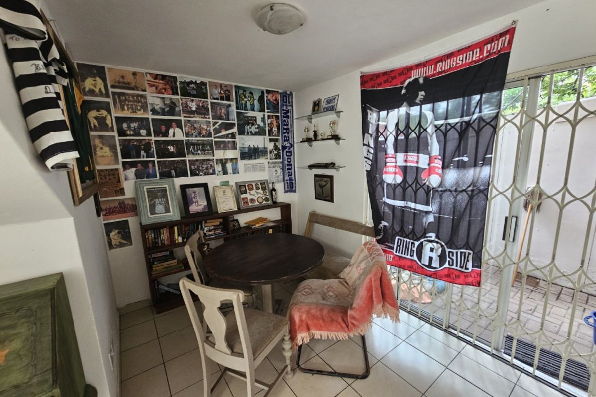 A living area featuring tiled flooring and a sliding glass door with a security gate, providing access to the exterior.