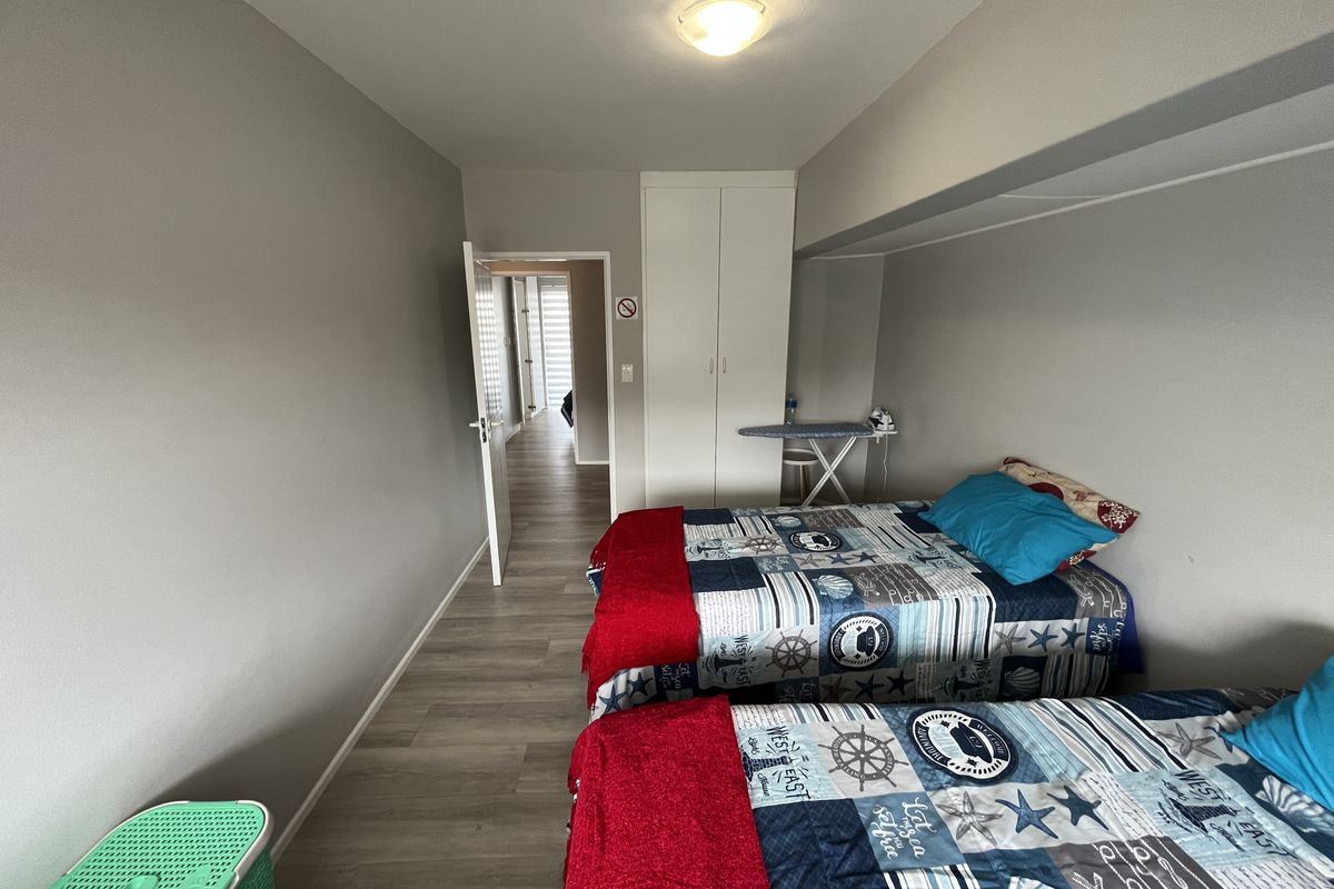 A functional bedroom featuring laminate flooring, a built-in wardrobe, and neutral wall finishes, providing a clean and practical living space.