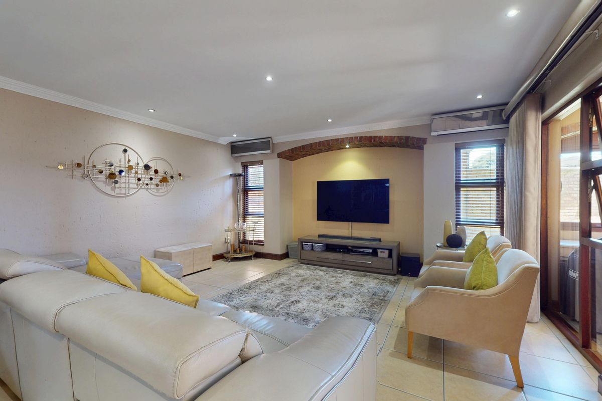 Spacious living room featuring tiled flooring, recessed lighting, an air conditioning unit, and a decorative brick arch feature above the television area.