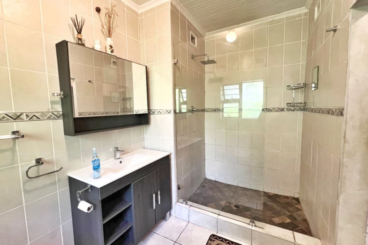 A functional bathroom featuring a walk-in shower with a glass screen, a modern vanity unit with basin, and neutral wall tiling.