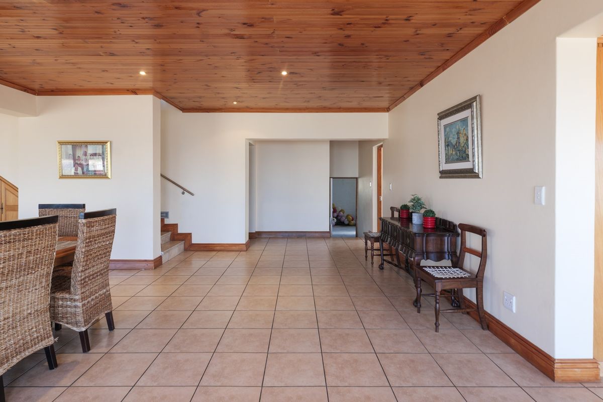 Spacious living area featuring a warm timber tongue and groove ceiling, neutral walls, and durable ceramic floor tiles throughout.
