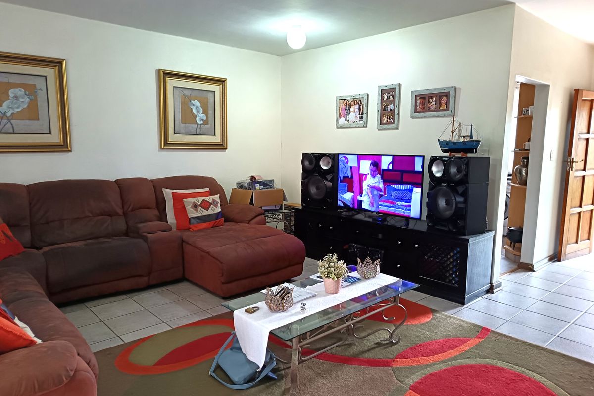 A living room featuring tiled flooring and access to an adjacent room, providing a functional space for relaxation.
