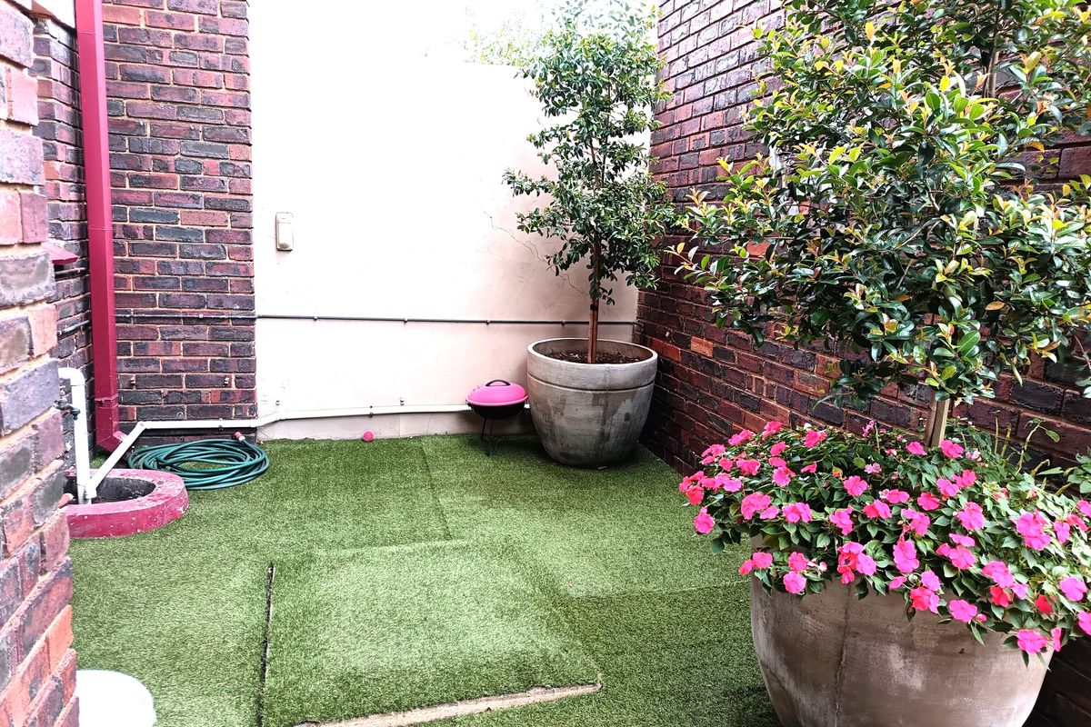 A private courtyard area featuring face-brick walls and artificial turf flooring, providing a low-maintenance outdoor space.