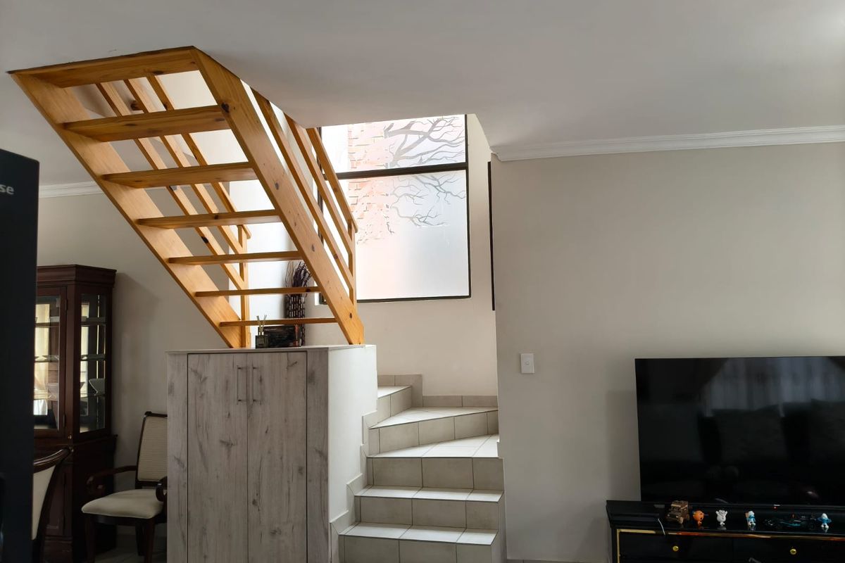 A living area featuring a unique combination of a wooden staircase and a tiled staircase with integrated storage underneath.