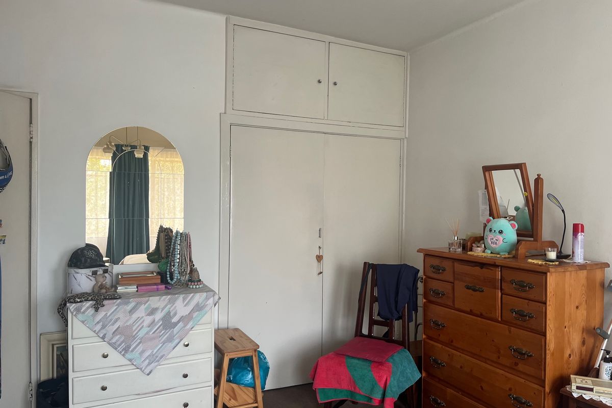 A bedroom featuring built-in cupboards with integrated overhead storage cabinets, providing functional storage space within the room.