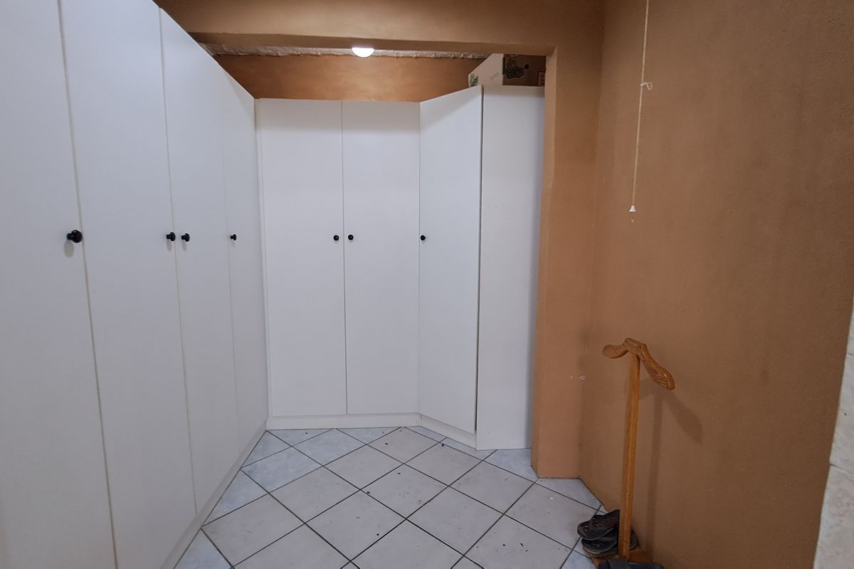 A bedroom area featuring extensive built-in white cabinetry and tiled flooring, offering ample storage space.