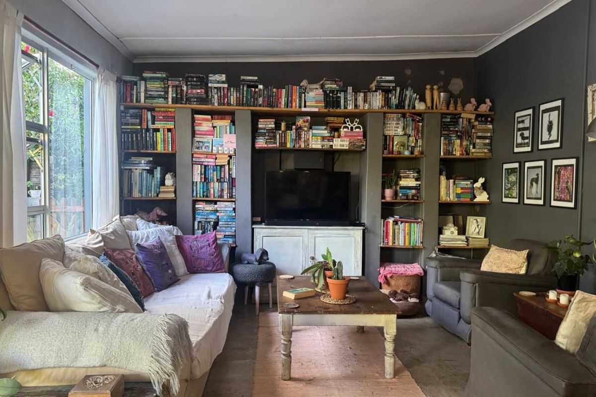 A cozy living room featuring extensive built-in floor-to-ceiling shelving and a large window providing natural light.